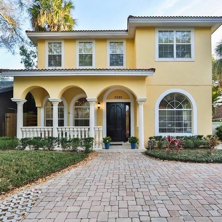 Large yellow house with a cobblestone walkway and pillars on a front porch with large windows. Photo by instagram user @tamparealtortaragocht