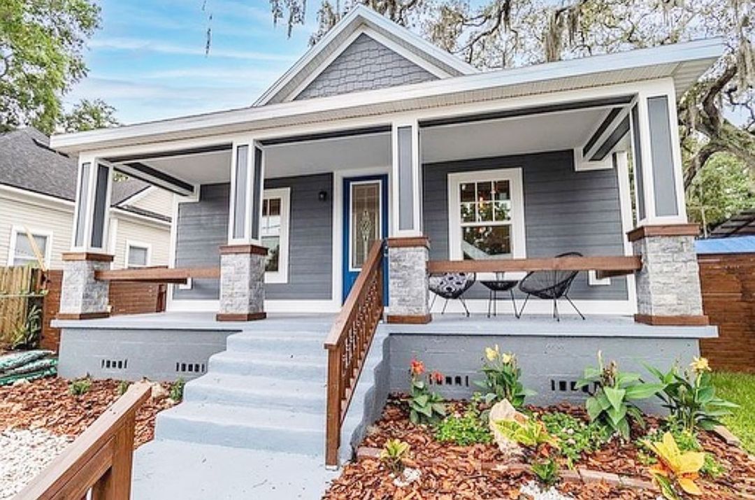 Modern gray bungalow with an open front porch and a garden in the front yard with wooden railings. Photo by instagram user @dr.kristina_kuba