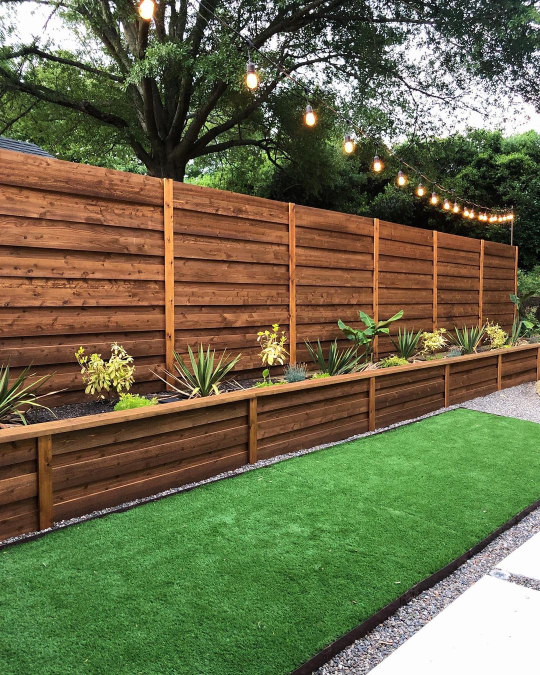 Modern backyard with built-in potted plants and an Edison light string. Photo by instagram user @flippinggvl