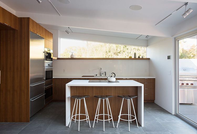 Modern kitchen with white walls and wooden features with a statement island and modern stools. Photo by instagram user @ klopfarchitecture