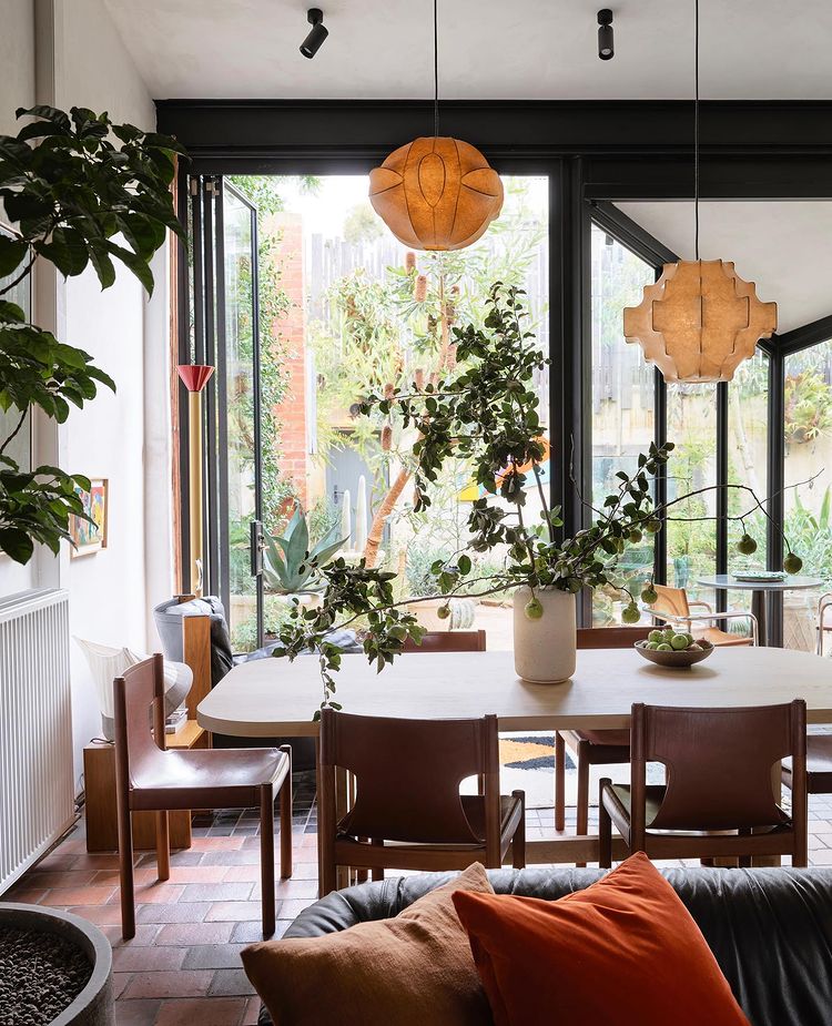 Modern dining room with wood features and plants with oversized windows that brighten up the room. Photo by instagram user @flackstudio_