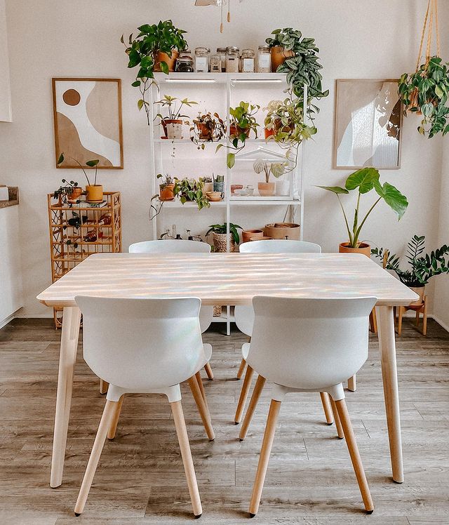 A modern kitchen with neutral colors, a wooden table, and houseplants throughout the room. Photo by instagram user @mybohemianjungle