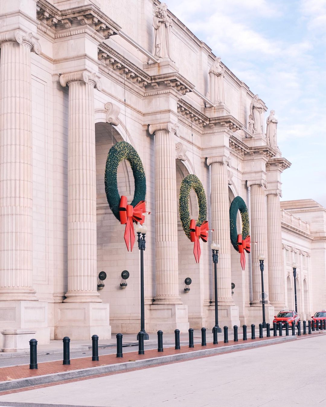 Festive image of union station in Washington, DC with decorative wreaths and large red bows. Photo by instagram user @laurajhaines