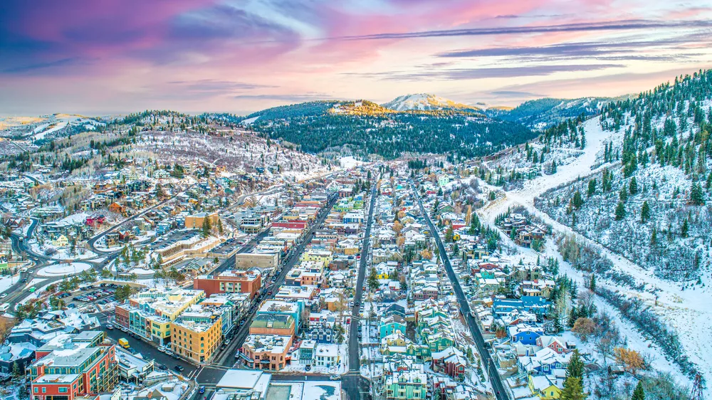 Arial shot of Park City, Utah, in the winter with a colorful landscape, painted houses, and a beautiful sunset.