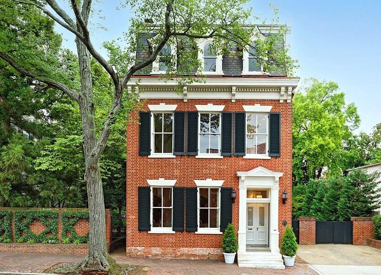 Three-story colonial brick house with wooden white trim and black shutters in a historic city with a garden wall covered in ivy. Photo by instagram user @tsghuntcountry