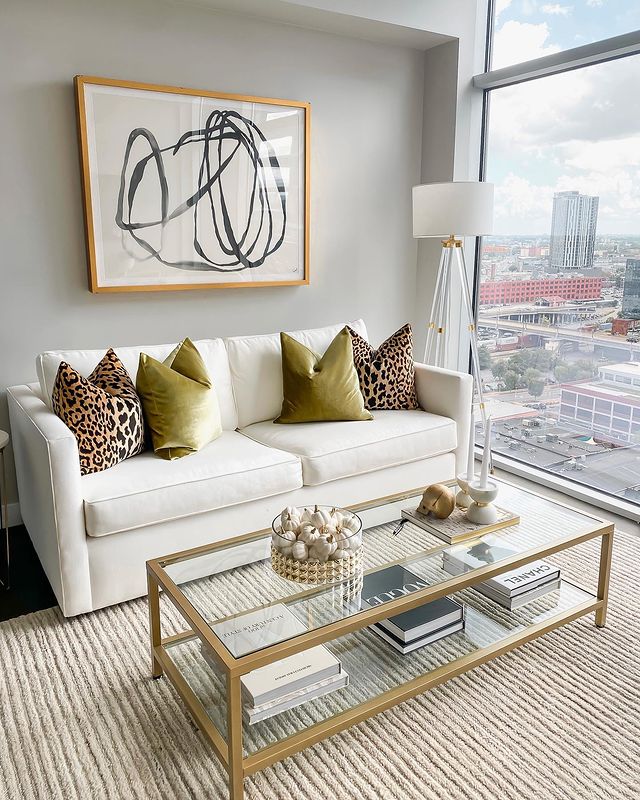 Modern living with a white couch, decorative pillows, a glass table, and wall art