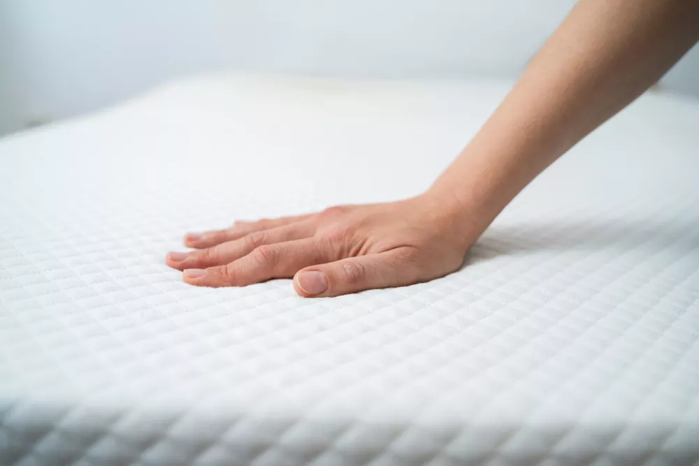 Stock photo of a hand testing an orthopedic white mattress