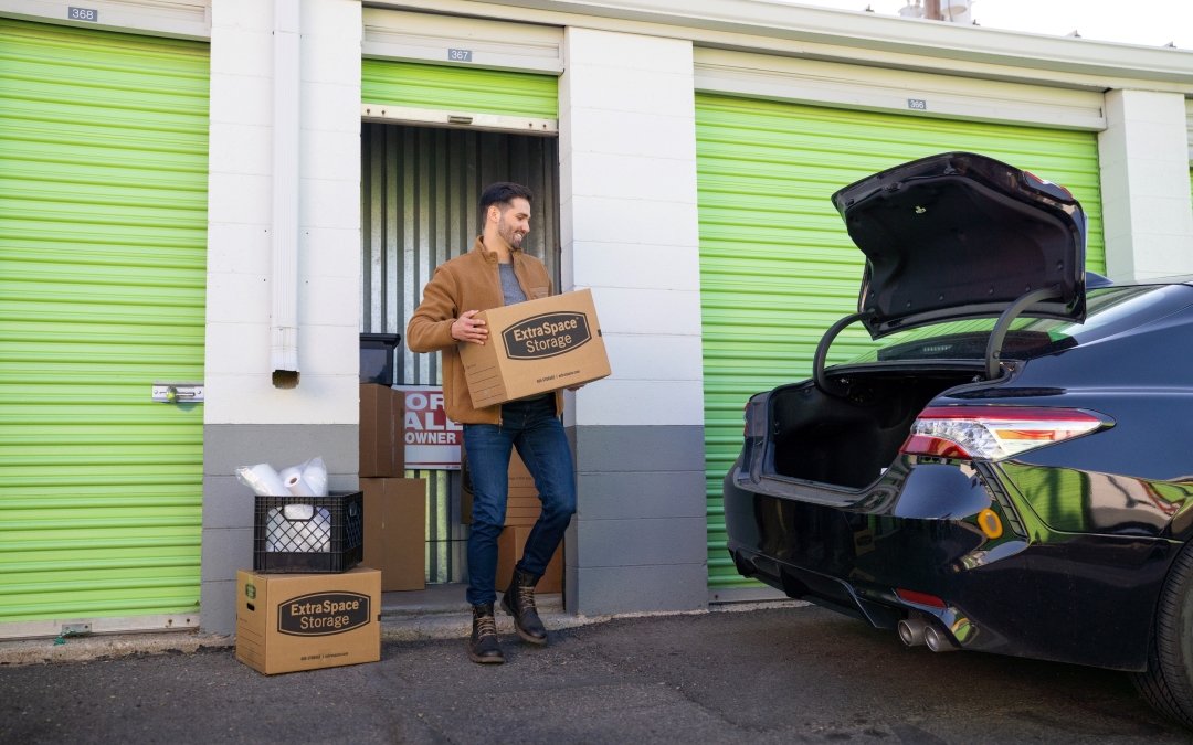 Man Carrying Extra Space Storage Boxes out of a Drive-Up Storage Unit