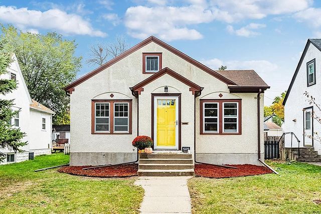 Quaint tan house with a yellow door and red landscaping in the Diamond Lake neighborhood of Minneapolis. Photo by instagram user @reidellesteyassociates
