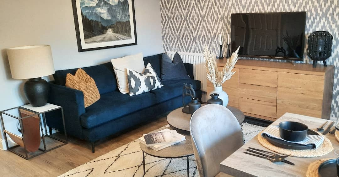 Interior view of modern living room with couch, chairs, and tv stand.