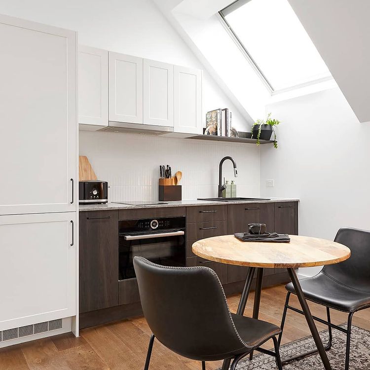 Interior view of modern kitchen with sink, cabinets, table, and chairs.