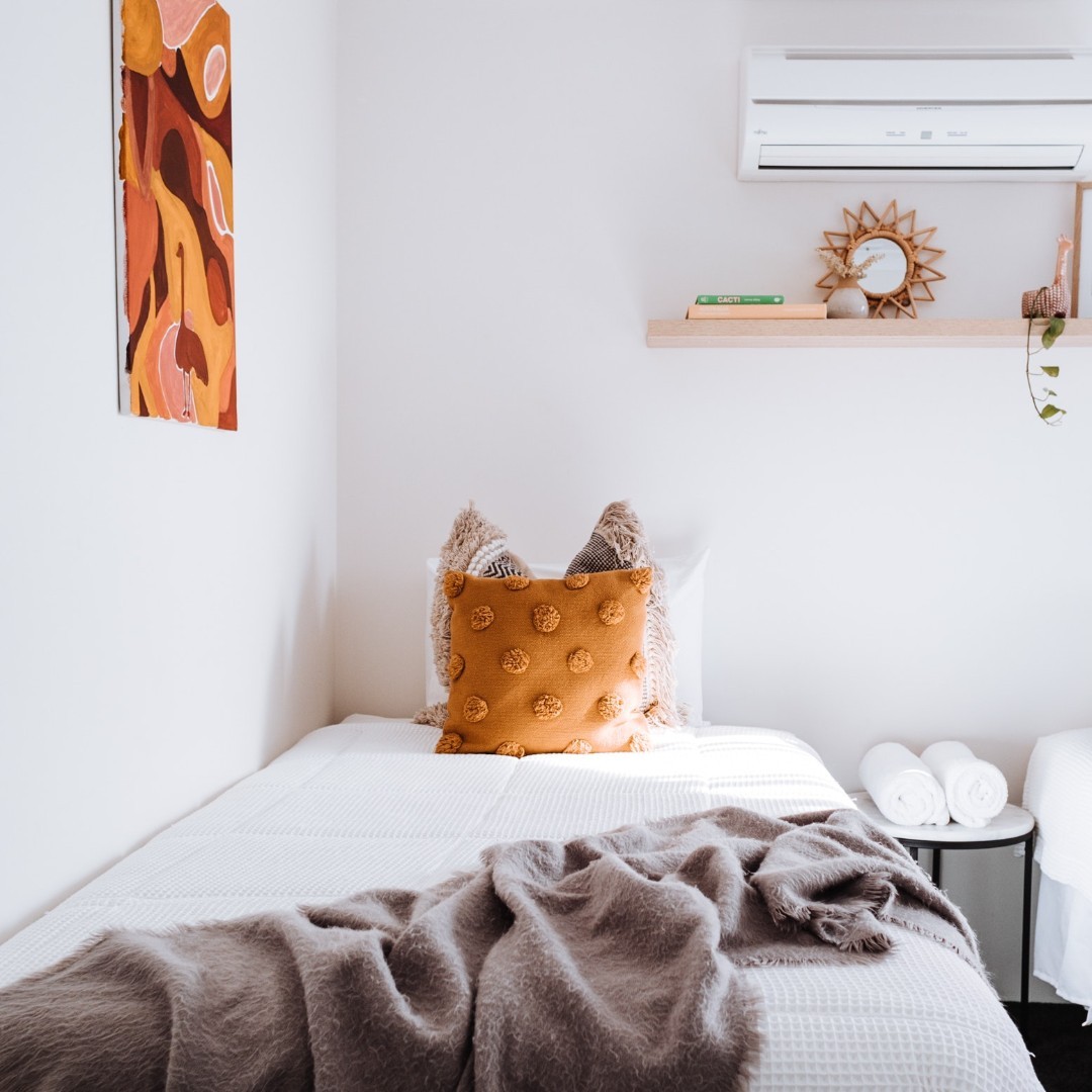 Interior view of modern bedroom with a comfy bed and orange decor.
