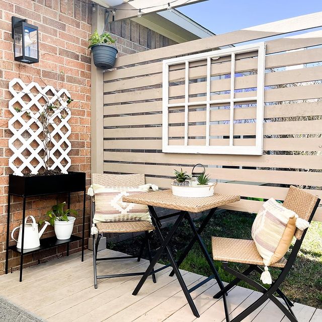 Exterior view of outdoor sitting area, complete with table, chairs, and wooden fence.