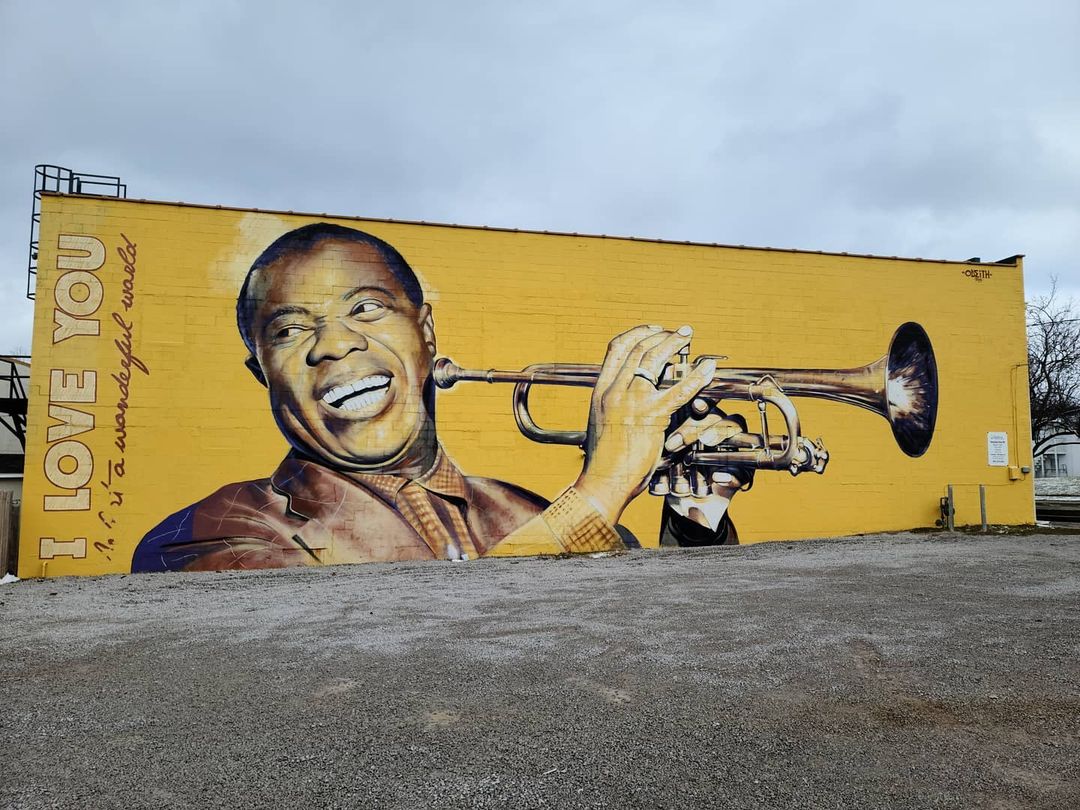 Bright yellow realistic mural of Louis Armstrong on the side of a building in Lexington, KY. Photo by instagram user @robystowe
