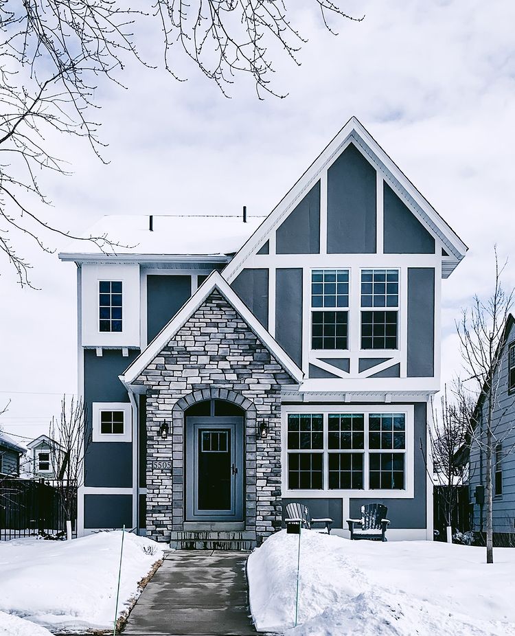 Beautiful gray house in the kenny neighborhood of Minneapolis with a mixed exterior made of wood and stone on a snowy day. Photo by instagram user @mattengengroup