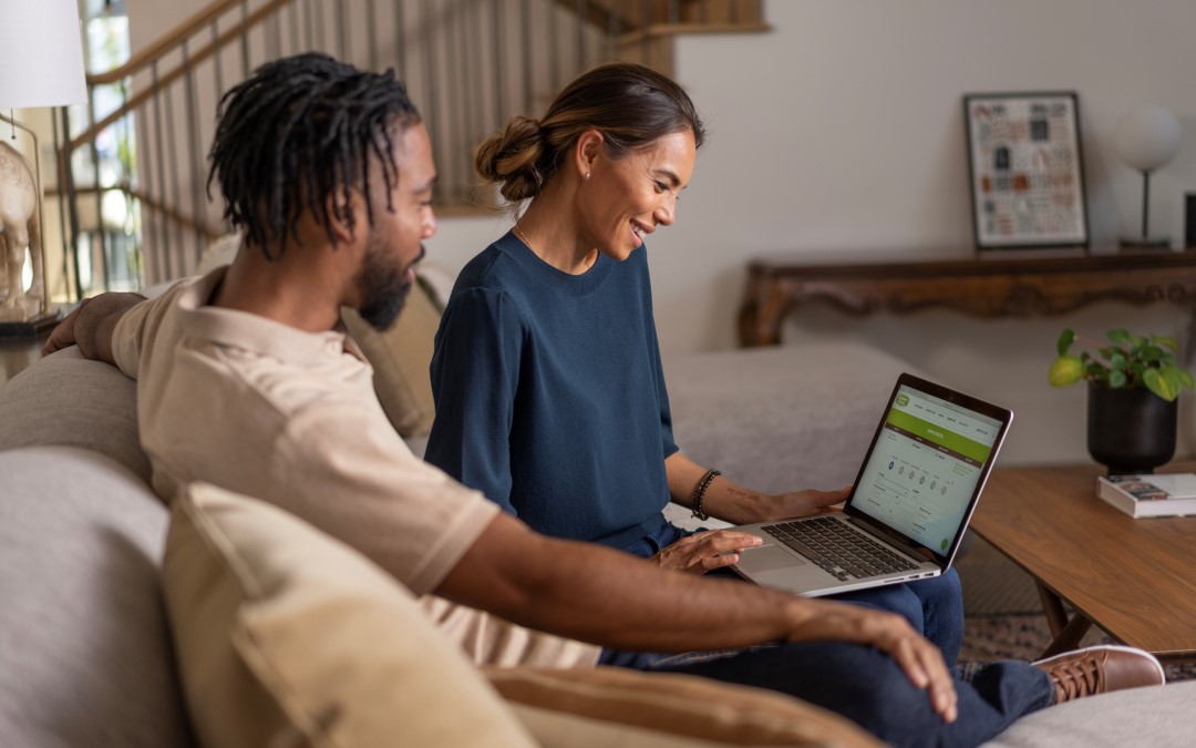 Couple in living room looking at Extra Space Storage website on laptop