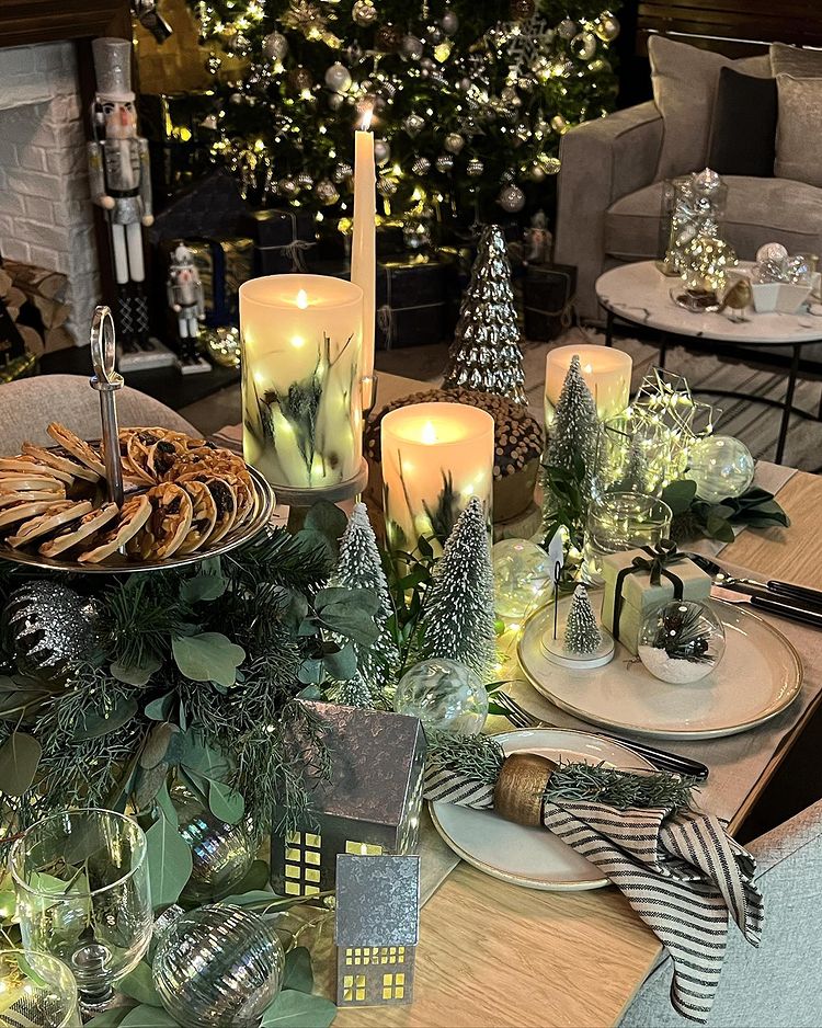 Christmas table with a lot of wood and pine features and striped cloth napkins and warm candles. Photo by instagram user @marksandspencer_james
