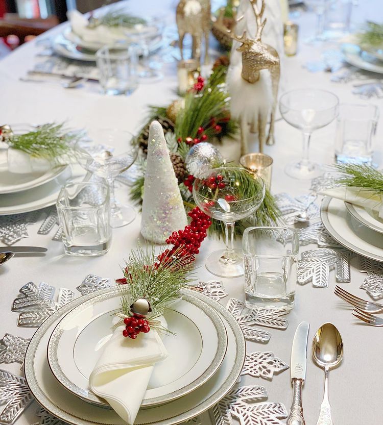 White Christmas table with some pine features with clear glasses and shining cutlery. Photo by instagram user @ohmycreativeparty