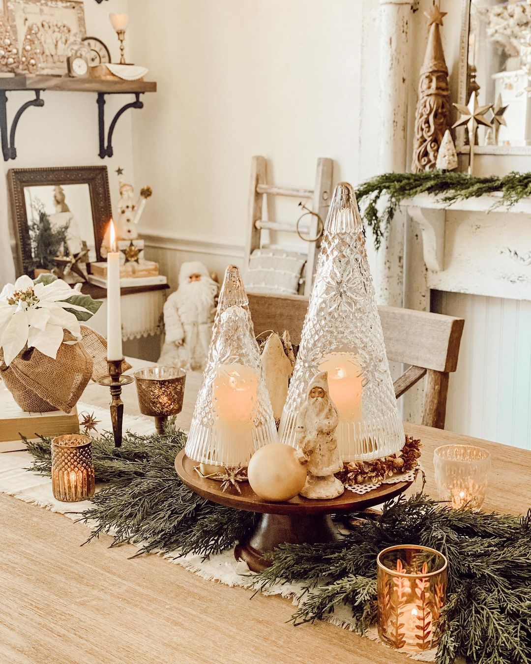 Rustic Christmas table with a crystal centerpiece surrounded by garland and candles on a wooden table. Photo by instagram user @courtneyfitzp01