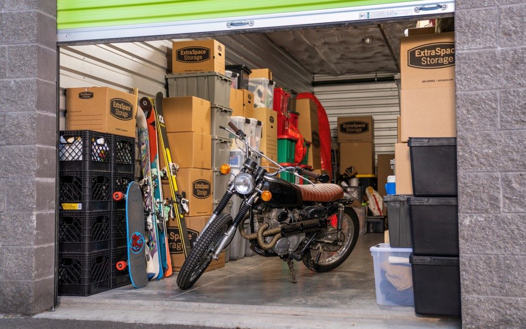 Motorcycle, moving boxes, and other belongings in drive-up storage unit.