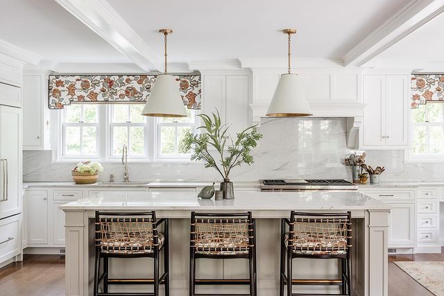 Interior view of kitchen with white marble island with chairs. 