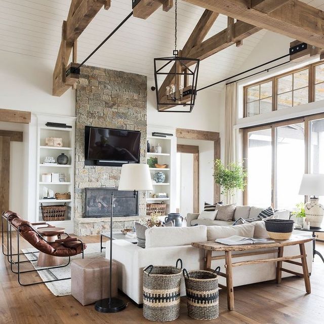 Interior view of living room with stone fireplace and wooden rafters.