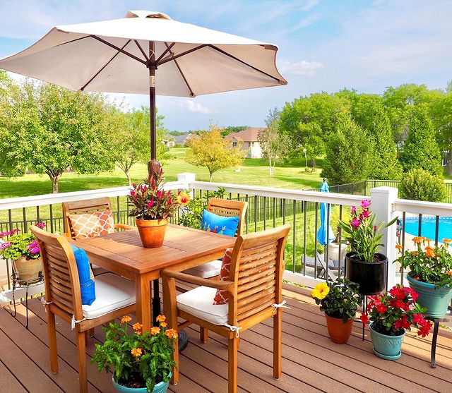 Outside photo of patio with table, chairs, umbrella, and pool 