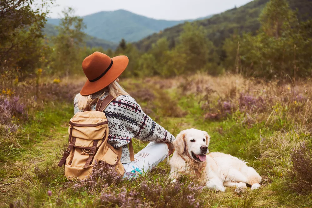 Woman sitting in field with golden retriever dog