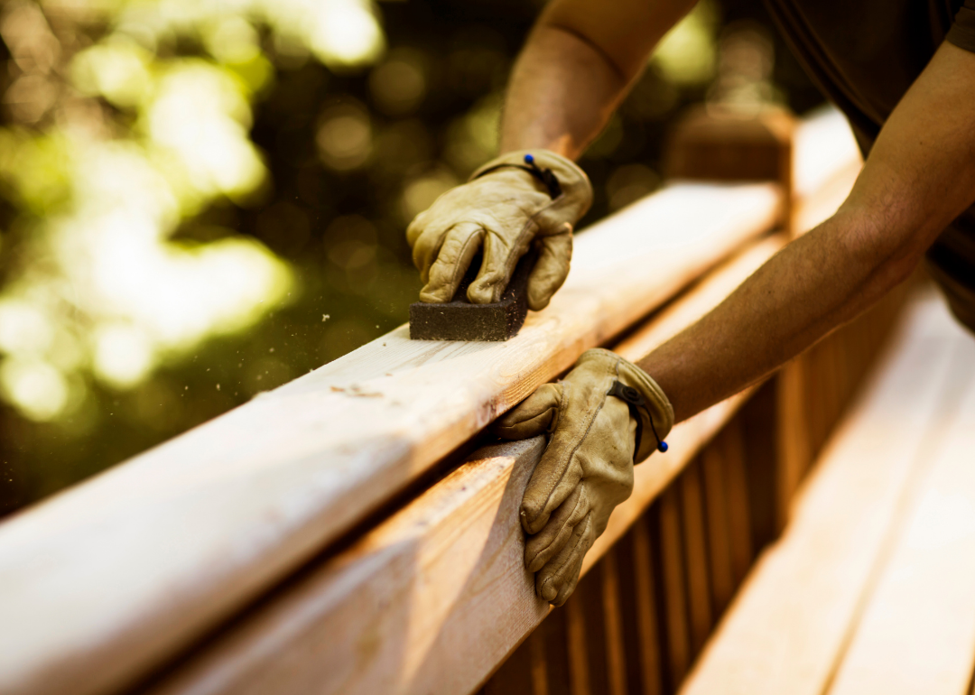 Man sanding wood deck balcony
