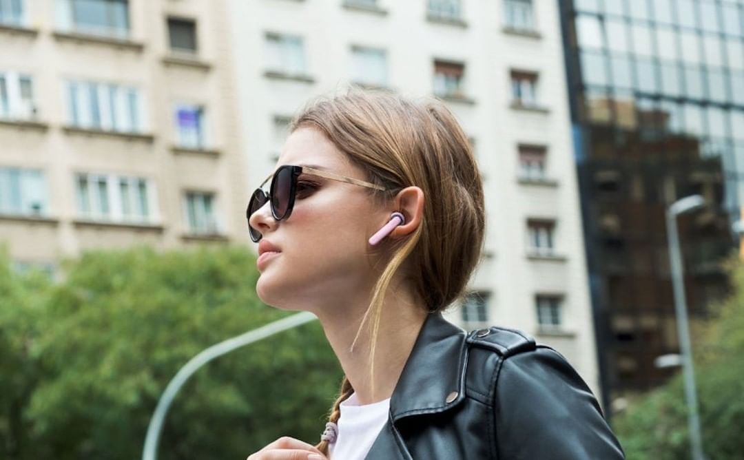 Woman wearing black leather jacket, sunglasses, and airpods while walking down the street listening to a podcast | Photo by Instagram user @gadgetflow