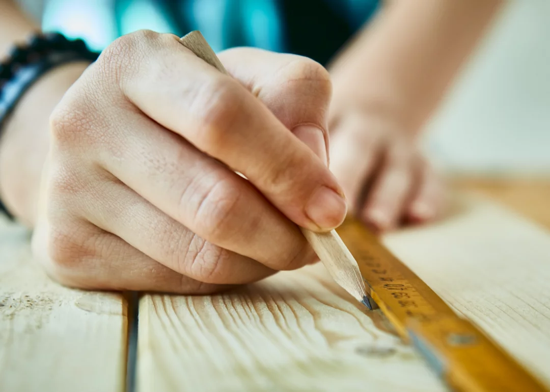 Man using ruler and marking wood board