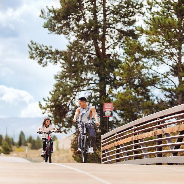 Man and child riding bikes across bridge. Photo by Instagram user @partyof4sometimes2