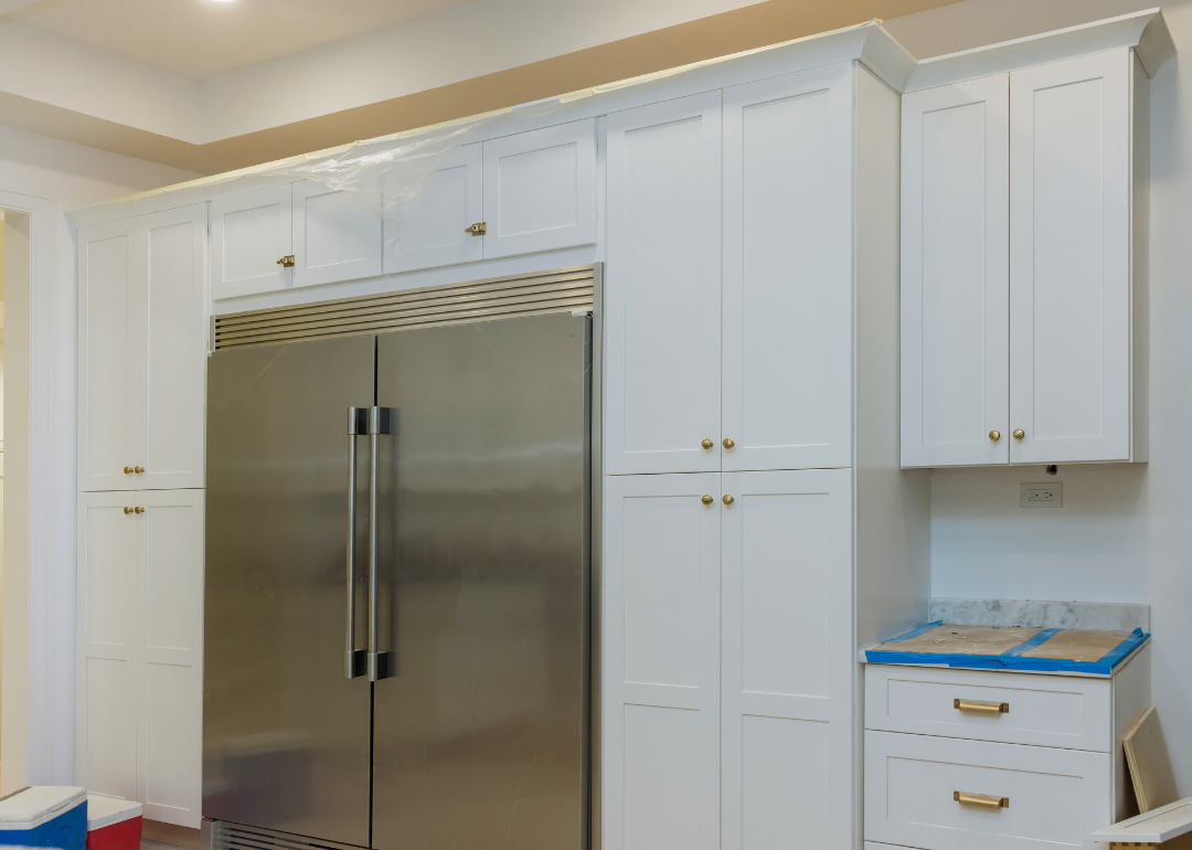 Interior of small kitchen with white cabinets and stainless steel fridge