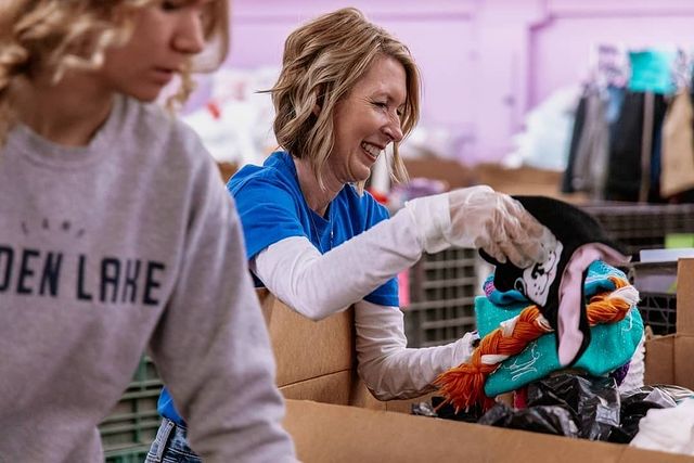 Female volunteer in blue tshirt packing a backpack with socks at Open Door Mission | Photo by Instagram user @opendoormission