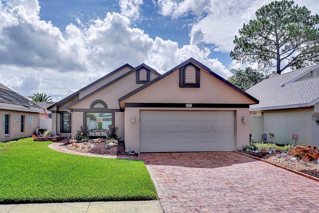 Exterior of a tan house with dark trim and a brick driveway in Orlando. Photo by Instagram user @teamreyes_cb_florida.