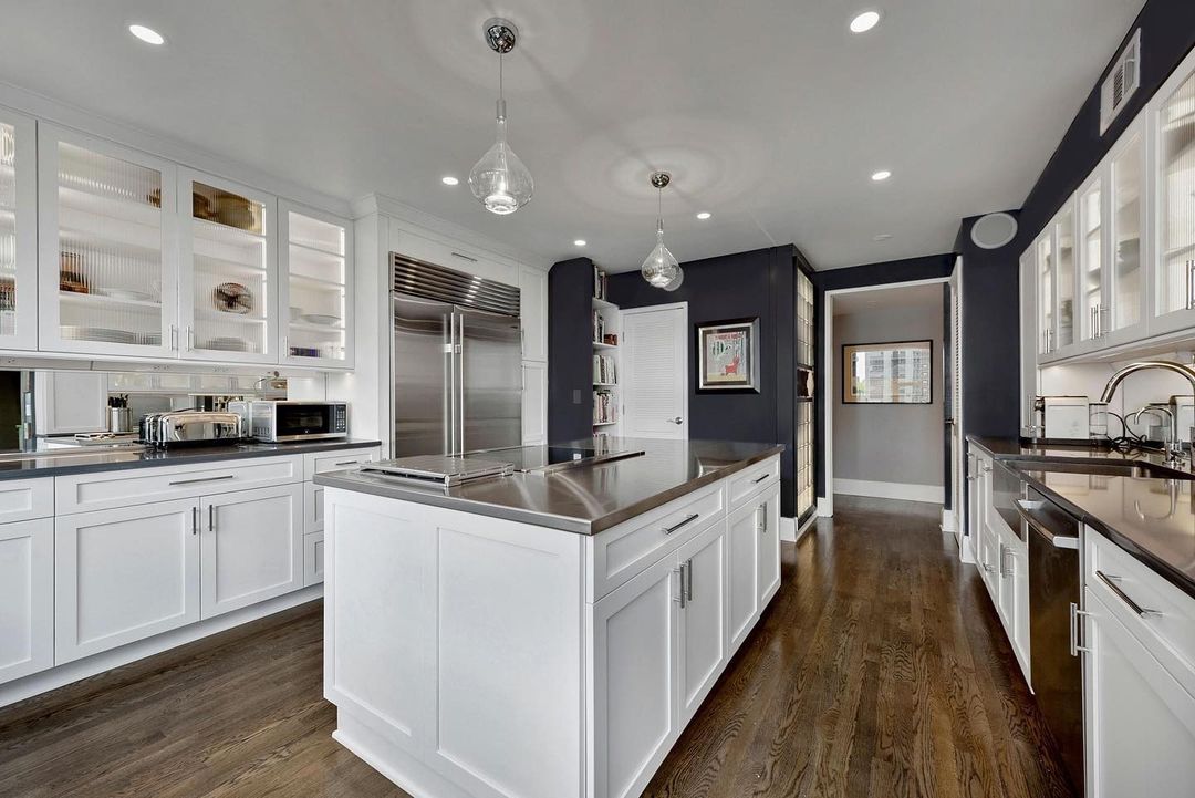 Kitchen with white cabinets and stainless steel countertops and appliances. Photo by Instagram user @arete_renovators.