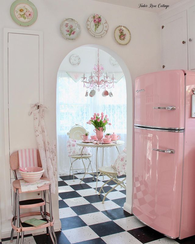 Kitchen interior with checkered linoleum and pink refrigerator. Photo by Instagram user @tudorrosecottage.