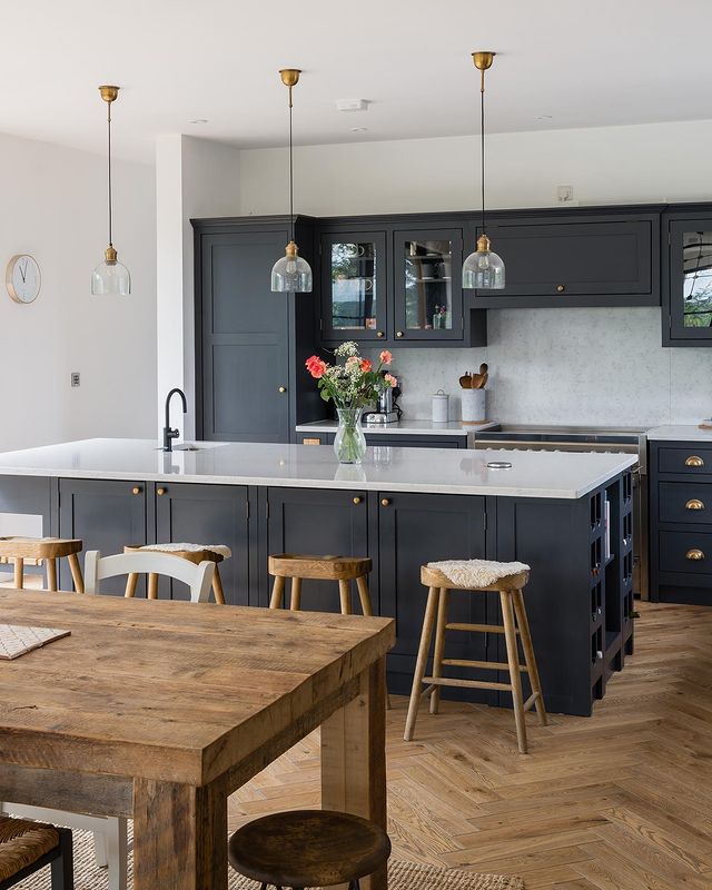 Kitchen interior with wood floors, dark cabinets, and white countertops. Photo by Instagram user @theshakerworkshop.