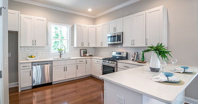 White cabinet kitchen with hardwood floors. Photo by Instagram user @reborncabinets