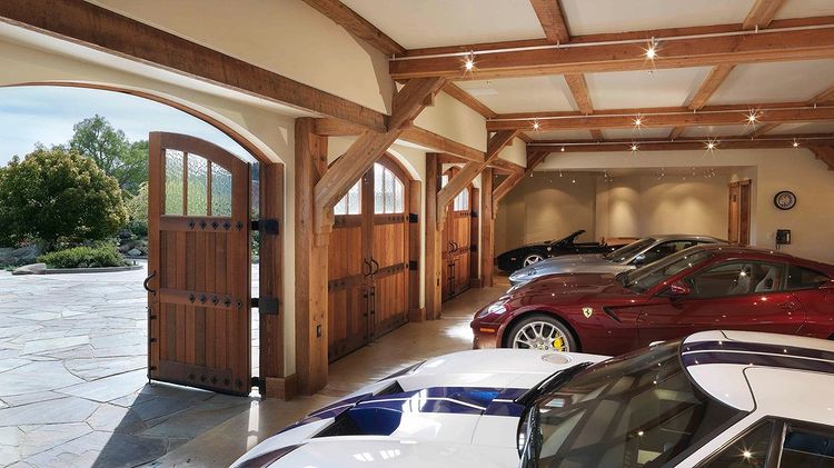 Interior of a garage with wood carriage doors and four cars. Photo by Instagram user @claudia_cook_