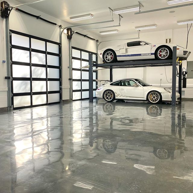 Interior of a garage with two cars on a car lift and glass garage doors. Photo by Instagram user @fasteddielee