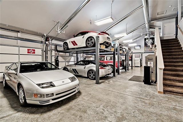 Interior of a garage with many luxury cars stacked on car lifts. Photo by Instagram user @bensellsnwa