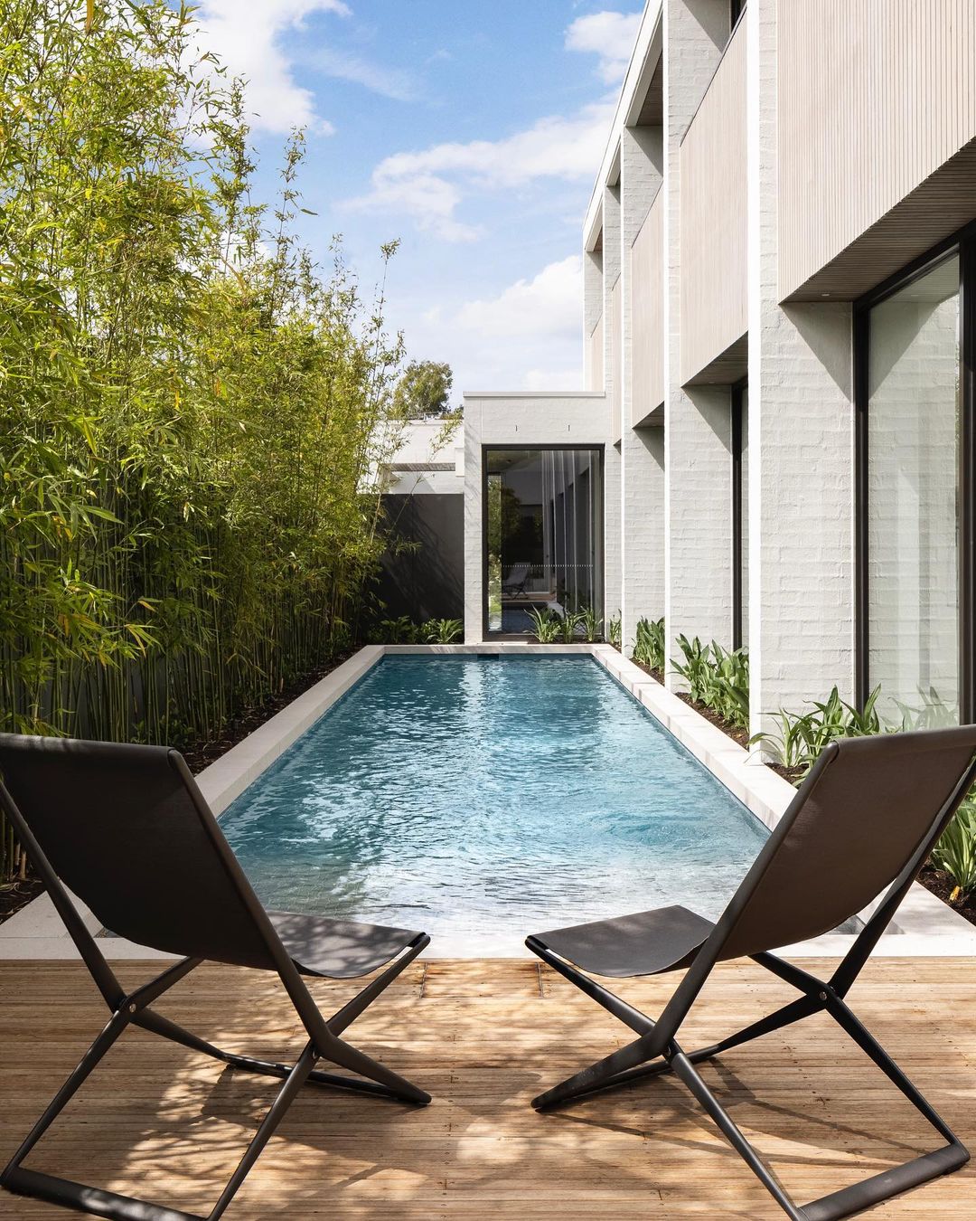 backyard lap pool with lounging chairs surrounded by greenery. photo via Instagram user @nathanburkett.nbla