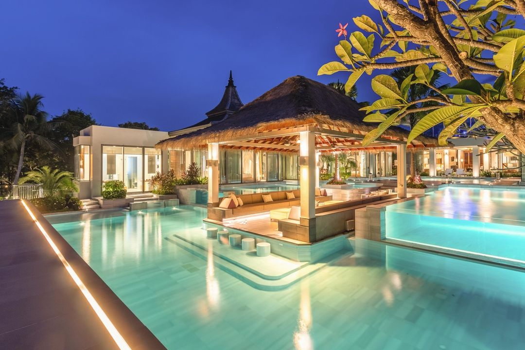 large swimming pool in a villa with conversation pit under a tiki style gazebo. Photo via Instagram user @theresortvilla