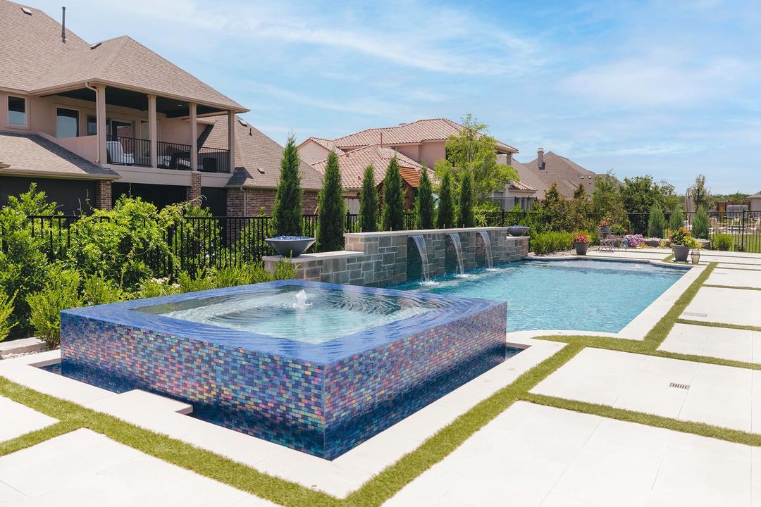 pool with waterfall and connected hot tub with iridescent mosaic tiles. Photo via Instagram user @claffeypools