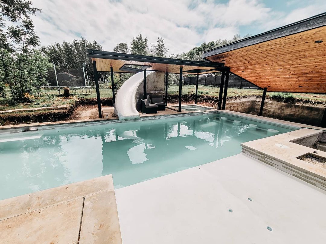 light blue backyard pool with zero entry and a white stone waterslide. Photo via Instagram user @theindiehome