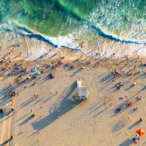Aerial view of Los Angeles beachgoers on sunny beach with bluegreen ocean waves