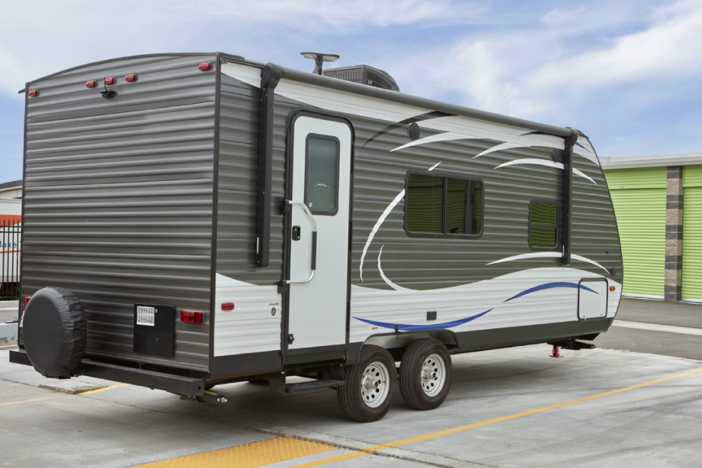 Gray and white camper in front of Extra Space Storage facility.