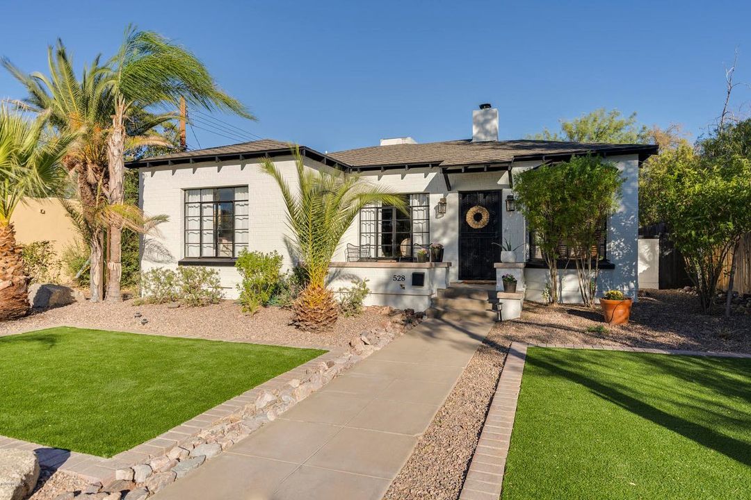 White style ranch home in Sam Hughes neighborhood with green lawn and sidewalk leading to door. Photo via @selltucson on Instagram