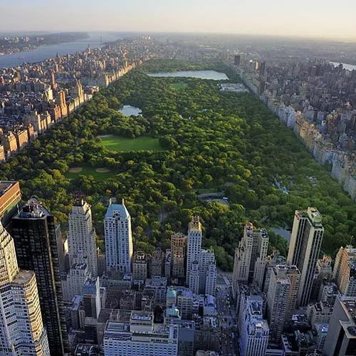 Aerial view of Central Park surrounded by skyscrapers with Hudson River in background